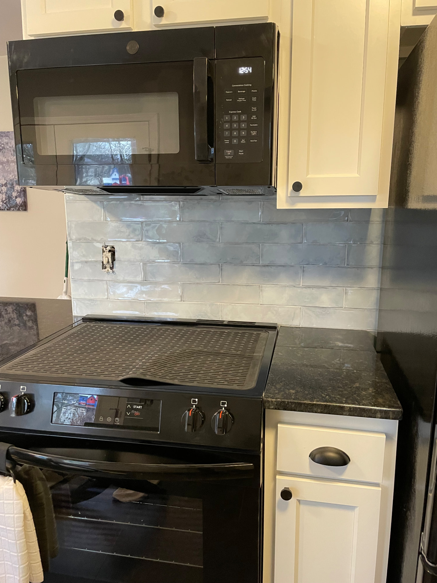 Kitchen stove and microwave with blue-gray subway tile backsplash and white cabinets in Frankfort, KY