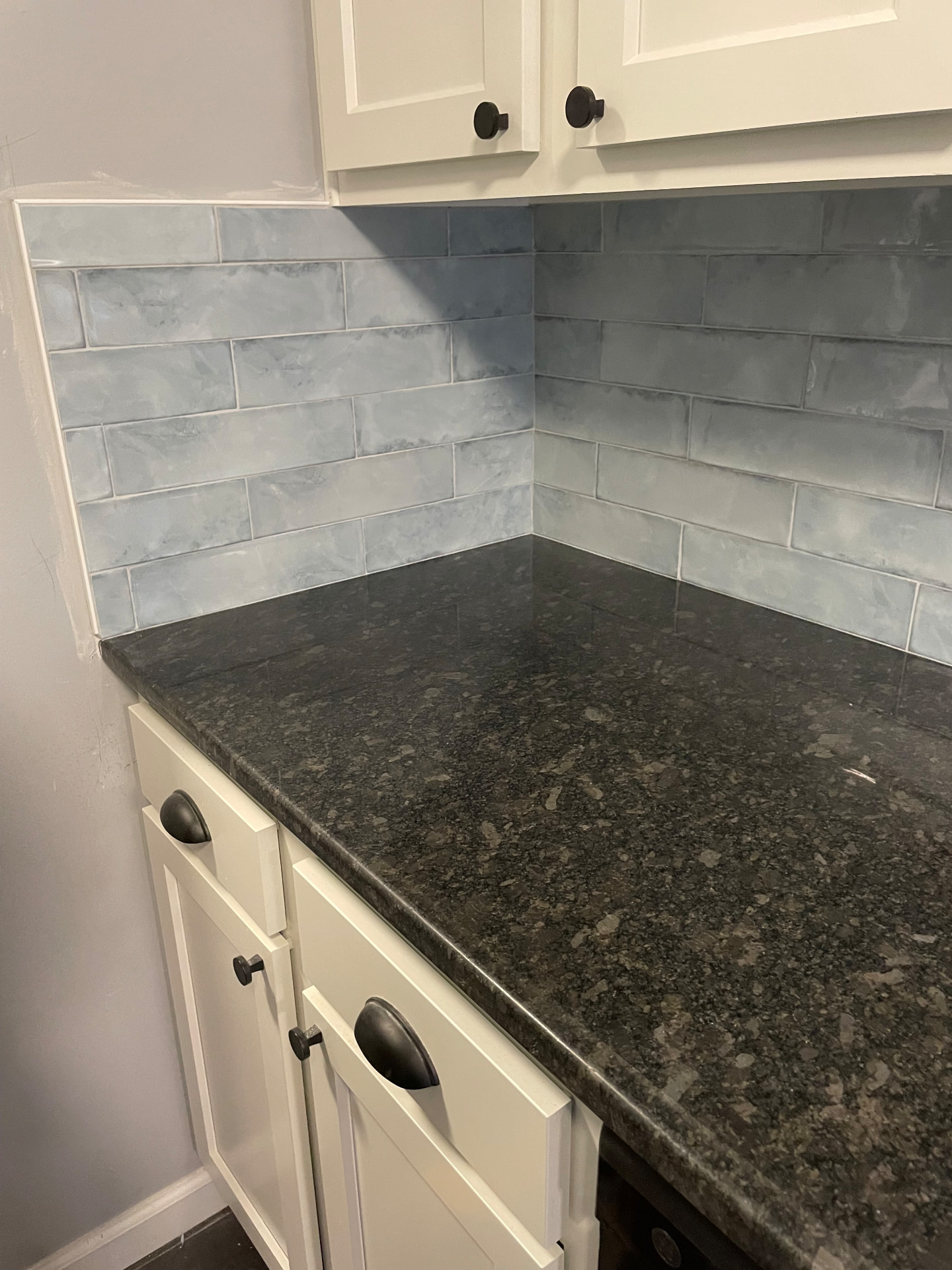 Kitchen corner with white cabinets, dark countertops, and blue-gray subway tile backsplash in Frankfort, KY