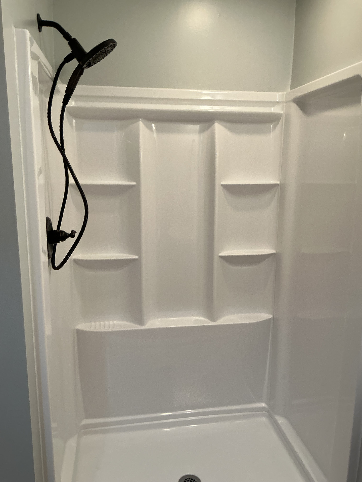 New white walk-in shower insert with black handheld shower fixtures in Georgetown, KY