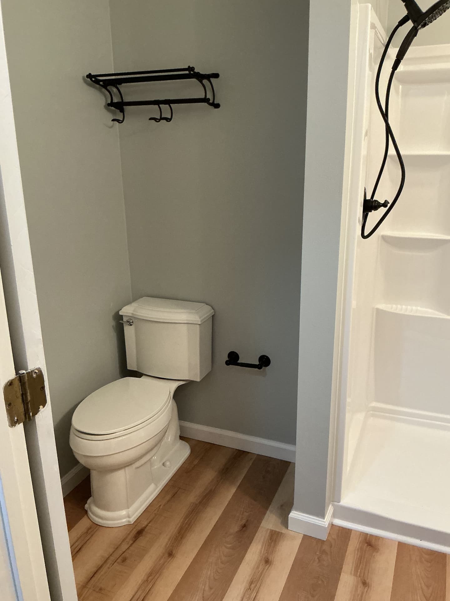 Remodeled bathroom with new toilet, black towel rack, and wood-look flooring in Georgetown, KY